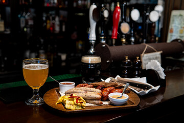 Sausages, snacks, light beer, and dark beer on a bar counter with taps in the back