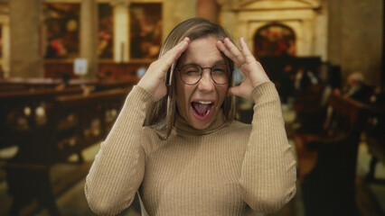 Blonde woman presses temples with hands inside church; playfulness joy.
