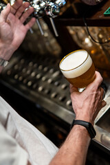 Pouring cold foamy beer in pub close-up