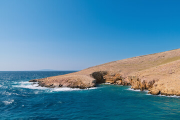 Rocky peninsula with clear blue sea and sky on sunny day