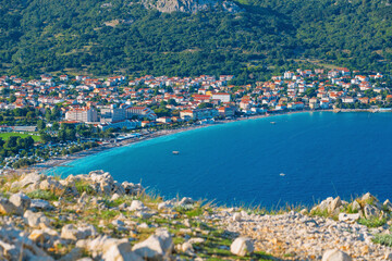 Naklejka premium Coastal town with vibrant blue sea and lush green hillside. Baška, Krk island, Croatia