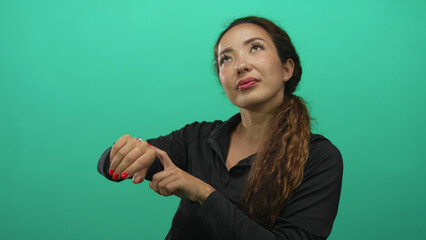Woman pointing at wrist and checking the time in studio green screen; anticipation time awareness now.