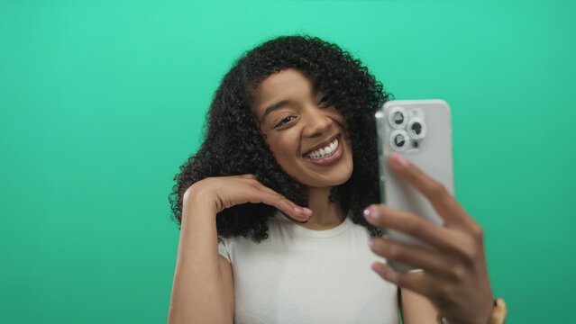 African american woman takes selfie with smartphone and flashes peace sign in studio; happiness.