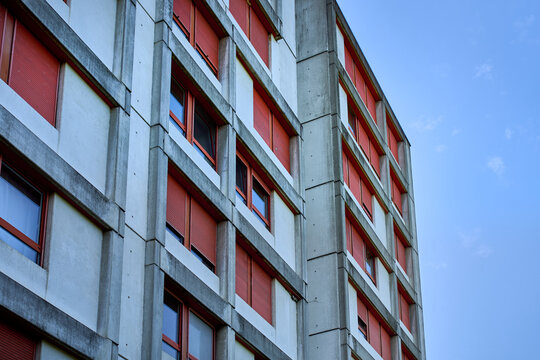 Concrete brutalist building in Kaiseraugst, Switzerland, features geometric lines and red window shutters, showcasing urban symmetry, functional design and minimalist Swiss lifestyle. Aargau canton