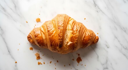 A freshly baked, golden-brown croissant sits atop a pristine white marble surface, its flaky layers hinting at a delicious and classic breakfast or a delightful sweet snack experience