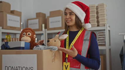 Obraz premium Woman organizing donations at charity center wearing santa hat sorting toys in festive indoor setting enhancing volunteer spirit and holiday joy helping community with generous contributions.