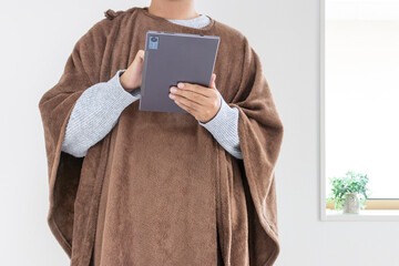 着る毛布を着てタブレット端末を使う男性（30代、日本人、顔無し）