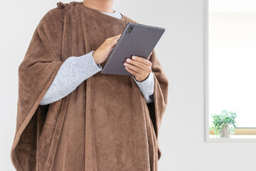着る毛布を着てタブレット端末を使う男性（30代、日本人、顔無し）