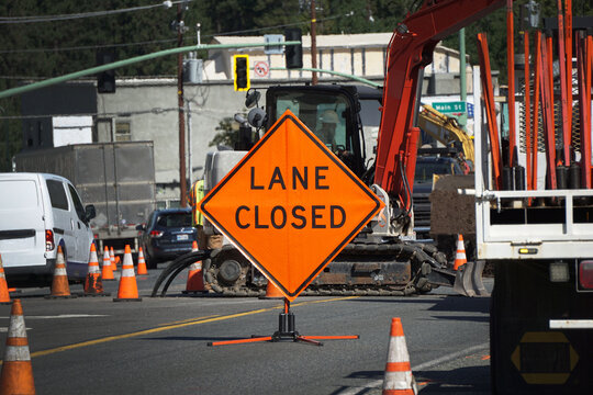 Road work and traffic with lane closed sign on street.