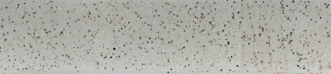 Texture of white glazed ceramic floor with crackle and black speckles