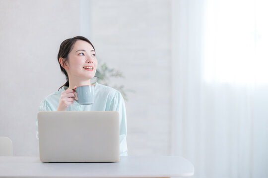 Woman drinking coffee while using her computer Looking up