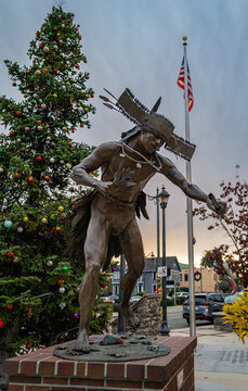 Auburn, CA U.S.A. - Dec. 2024: The Nisenan Dancer sculpture by Douglas Van Howd in Auburn&rsquo;s Central Square stands beside a decorated Christmas tree in early evening holiday light.