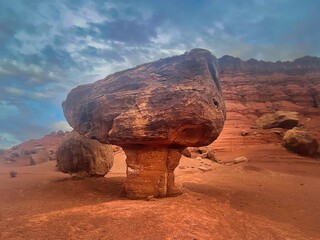 Large rock balances on a small spire of dirt 