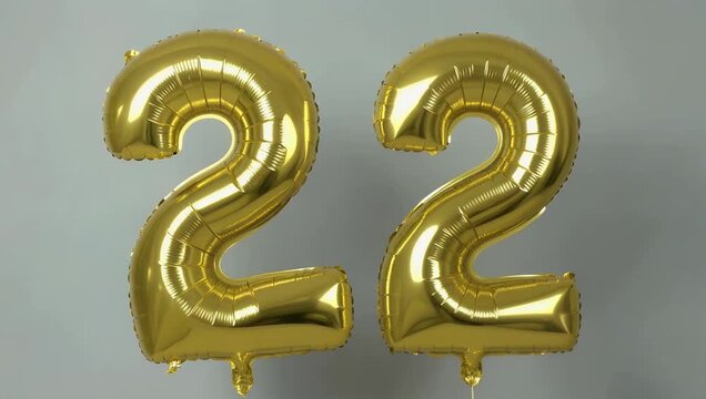A looping 4K shot of a shiny gold foil balloon shaped like the number two floating against a clean background ideal for anniversaries milestone celebrations birthdays or festive decoration scenes