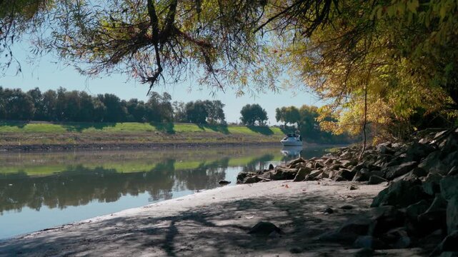 Boat Cruising on the Sacramento River, Framed by Fall Foliage and Levees