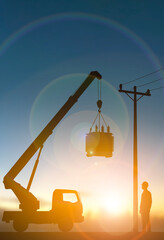 Silhouette Crane Lifting Electrical Transformer at Sunset