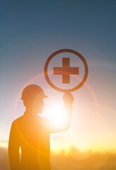 Silhouette Worker Holding Safety Symbol at Sunrise