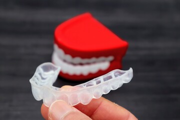 歯の矯正用のマウスピースを持つ人物のクローズアップ