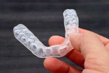 歯の矯正用のマウスピースを持つ人物のクローズアップ