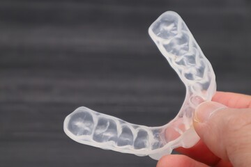 歯の矯正用のマウスピースを持つ人物のクローズアップ