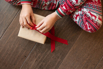 Hands of child tying bow on christmas present
