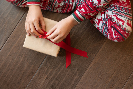 Hands of child tying bow on christmas present