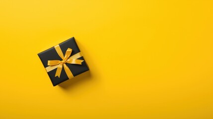 Black gift box with yellow ribbon on a vibrant yellow background.