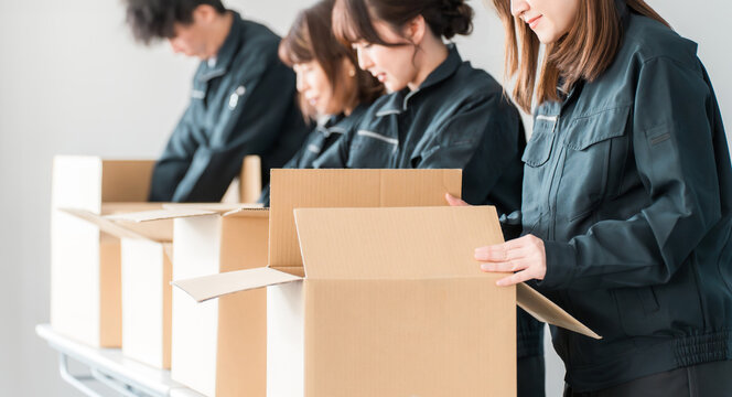 Male and female workers of transportation, logistics, courier, distribution, delivery, warehouse, and delivery companies who pack items into cardboard boxes
