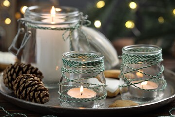 Christmas lanterns, cookies and festive decor on table against background with blurred lights, closeup. Bokeh effect