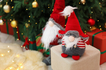 Funny gnomes near Christmas tree and gift boxes in decorated room