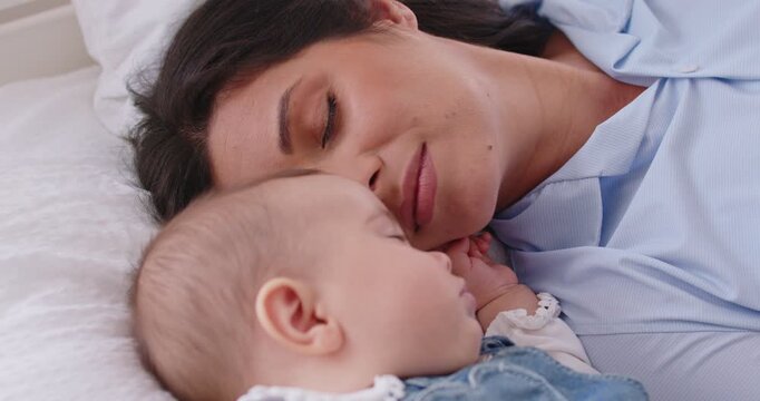 Loving care protecting mother, baby lying closely on white bed at home, small child sleeping calmly parent resting nearby, feeling peaceful and serene in good calm tender bonding safe home together 