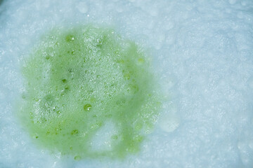 Extremely close texture of matcha green tea latte with soft-focus milk froth. Ideal for modern background use in food graphic design.