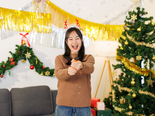 Asian young beautiful woman smile shooting paper cracker confetti rainbow colored paper fireworks decorated christmas tree background Merry christmas happy new year season holiday festival celebrated.