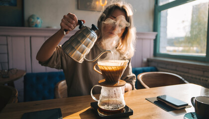 Barista pouring hot water for manual pour-over coffee brewing in a cozy café.