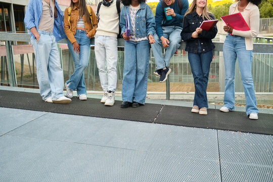Diverse group of college students standing together, discussing on a modern university campus