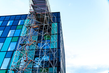 Green glass exterior of office building rising skyward with scaffolding