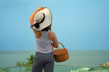 Woman in Hat with Picnic Basket Overlooking Ocean