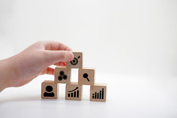 Hand Arranging Wooden Blocks with Business Icons