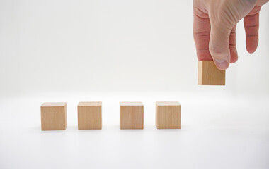 Hand Placing Wooden Block on White Background