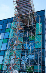 Green glass exterior of office building rising skyward with scaffolding