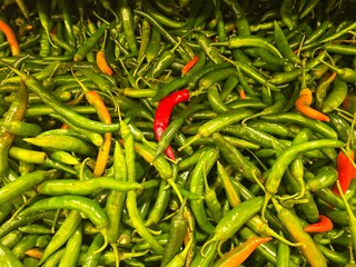 A large, dense pile of fresh green chili peppers (likely bird's eye chilies or small finger chilies).