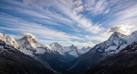 Fototapeta premium Jagged peaks and valley under a streaked sky. Snow covers the mounts