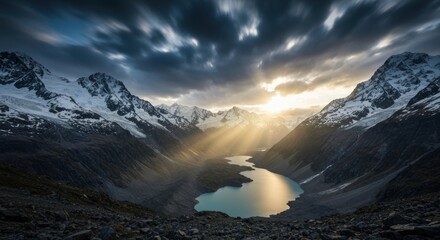 Dramatic light over snow-capped mountains, illuminating a glacial lake