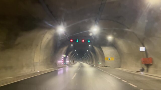 A view of a car moving through a long tunnel, illuminated in a fast and dynamic way. Travel, transportation, speed.