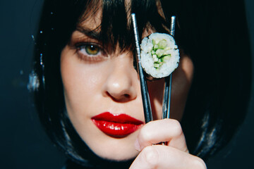 A stylish woman with a bob hairstyle showcases sushi with chopsticks, emphasizing contemporary...