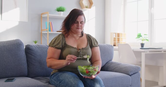 Slimming vegetarian diet, eating green vegetables, veggies salad menu for dinner, pleasant obese woman sitting at home, chubby overweight plus size big fat fit lady sad with no progress in weight loss