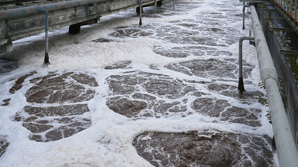 Treatment facility manages wastewater with foam on the surface during afternoon operations near...