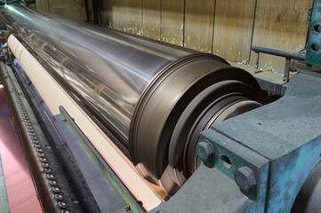 Machinery operation at a paper mill focusing on the paper machine in action