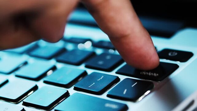 Finger of the computer user, he presses the delete button on the computer keyboard	