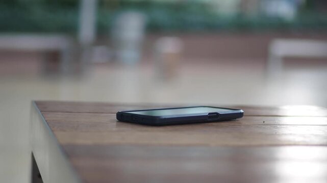 Close-up view of a smartphone on wooden table outdoor, lost smart phone concept